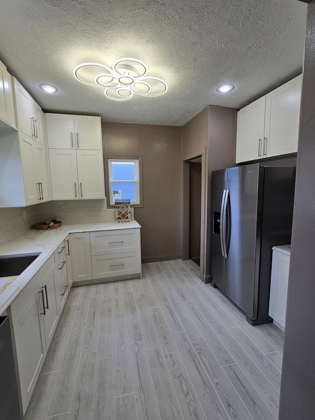 601 Powell St, Streator, IL 61364 - kitchen with dishwashing machine, light wood-style flooring, a textured ceiling, light countertops, and stainless steel fridge