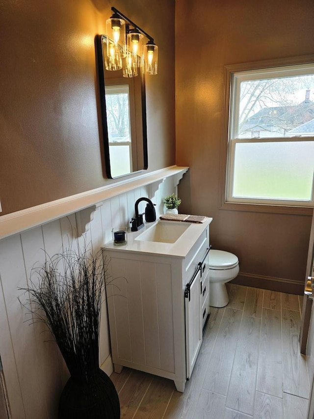 601 Powell St, Streator, IL 61364 - bathroom with a healthy amount of sunlight, a chandelier, toilet, and wood finished floors