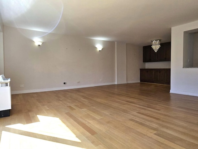 1115 S Plymouth Ct Unit 303, Chicago, IL 60605 - unfurnished living room with light wood-style flooring, baseboards, and an inviting chandelier