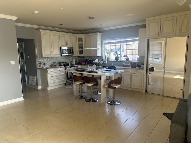 kitchen featuring glass insert cabinets, a center island, appliances with stainless steel finishes, a kitchen breakfast bar, and backsplash