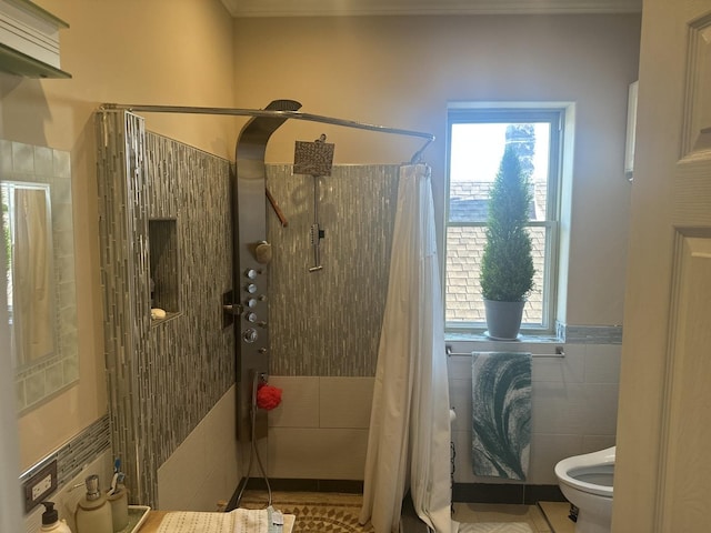 bathroom with toilet, crown molding, tiled shower, and tile walls