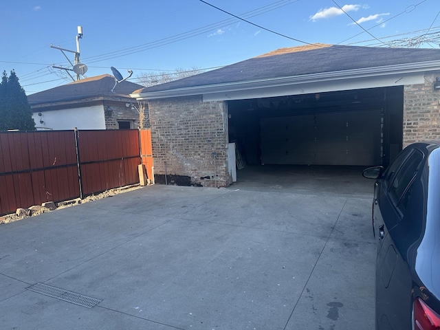 garage featuring concrete driveway and fence