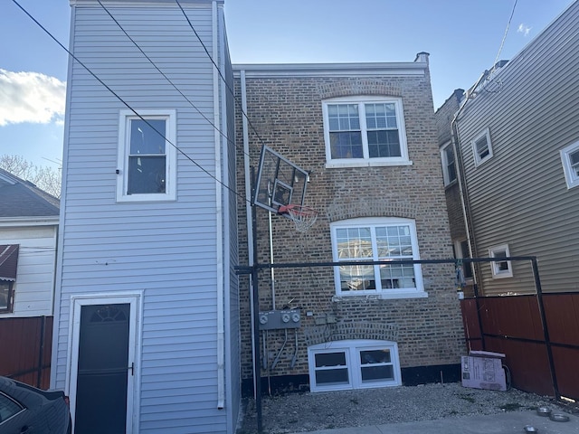 back of property featuring brick siding and fence