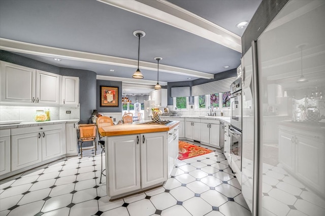 kitchen featuring white cabinets, a center island, a sink, and light floors