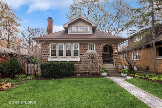 view of front of house featuring a front lawn, brick siding, and a chimney