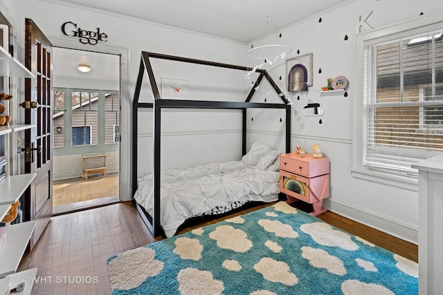 bedroom featuring baseboards, wood finished floors, and ornamental molding