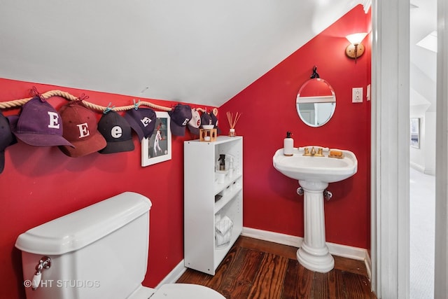 bathroom with vaulted ceiling, wood finished floors, toilet, and baseboards