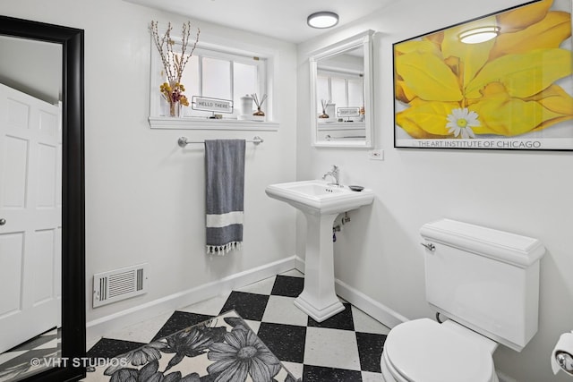 half bathroom with toilet, tile patterned floors, visible vents, and baseboards