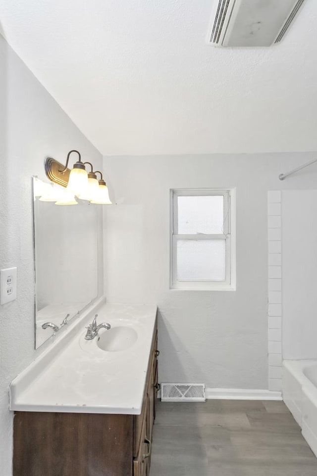 full bathroom with visible vents, baseboards, washtub / shower combination, vanity, and wood finished floors
