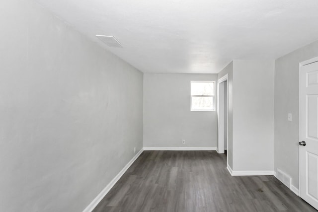 empty room with baseboards, dark wood finished floors, and visible vents