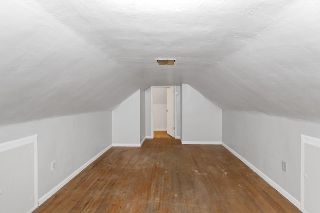 additional living space with lofted ceiling, baseboards, and wood finished floors