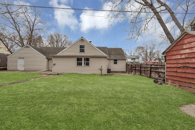 rear view of property featuring fence and a lawn