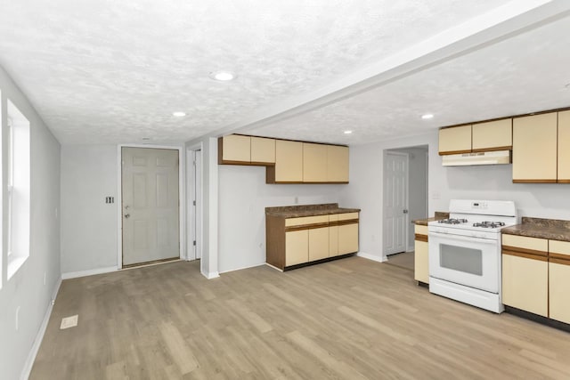 kitchen with light wood-style floors, white range with gas cooktop, cream cabinetry, under cabinet range hood, and baseboards