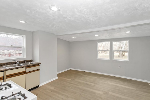 kitchen with a sink, light wood-style flooring, recessed lighting, and baseboards