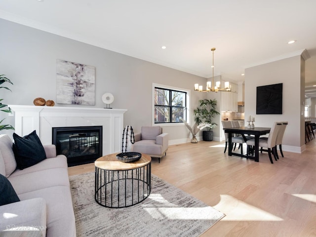 living area featuring light wood-style flooring, ornamental molding, a chandelier, a premium fireplace, and baseboards