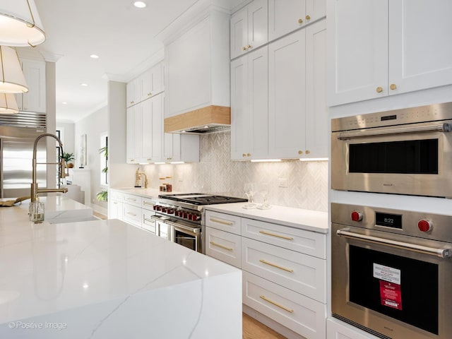 kitchen with decorative backsplash, high end appliances, custom range hood, and white cabinets