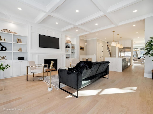 living room with built in features, a fireplace, beamed ceiling, light wood finished floors, and coffered ceiling