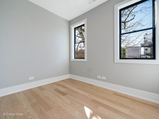 spare room featuring light wood-style floors, baseboards, and visible vents