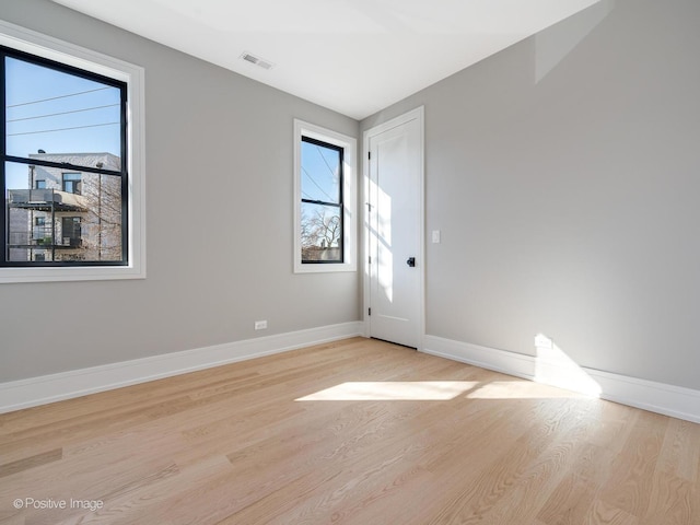 spare room with light wood-style floors, baseboards, and visible vents