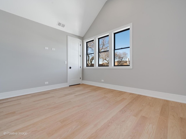 unfurnished room featuring light wood-style floors, high vaulted ceiling, visible vents, and baseboards