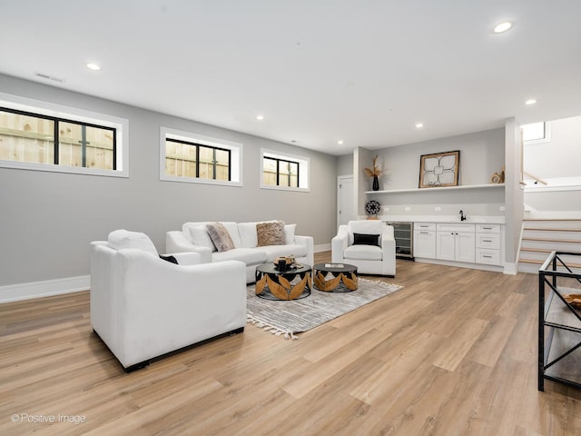 living room with visible vents, light wood-type flooring, baseboards, and indoor bar