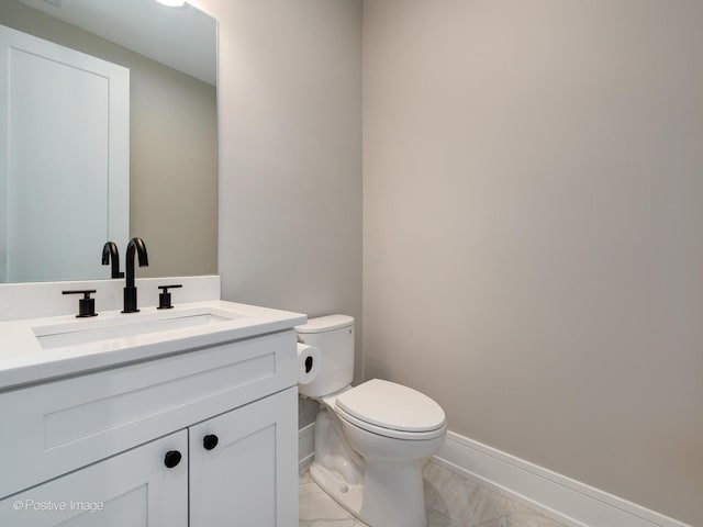 bathroom featuring toilet, vanity, and baseboards