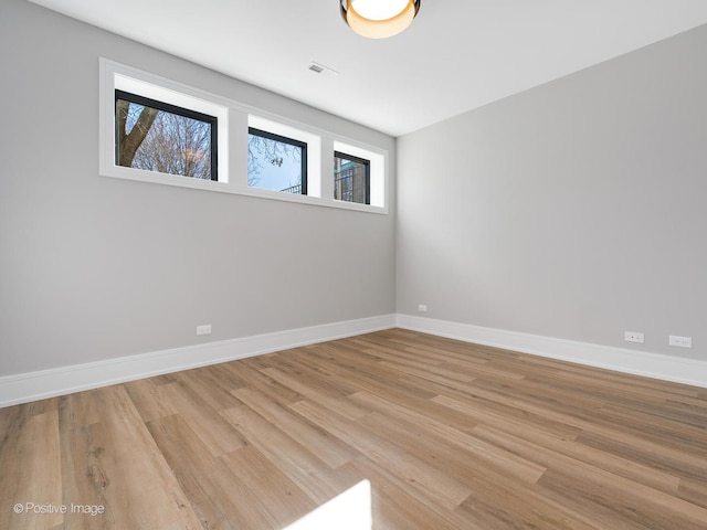 spare room featuring wood finished floors, baseboards, and plenty of natural light