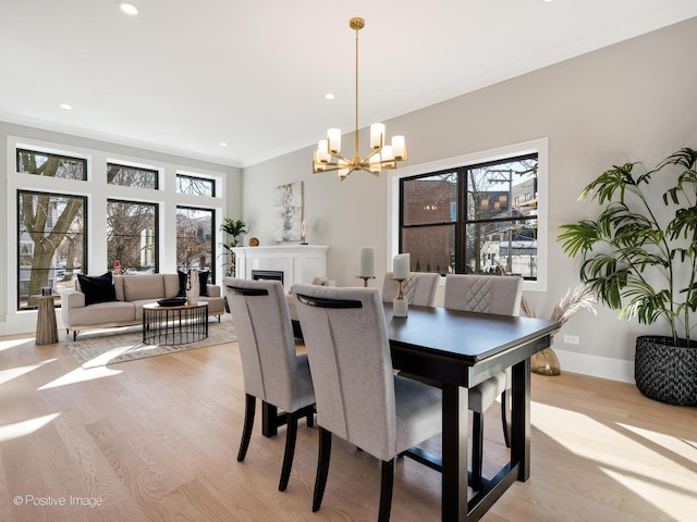 dining room with a notable chandelier, baseboards, ornamental molding, recessed lighting, and light wood-style flooring