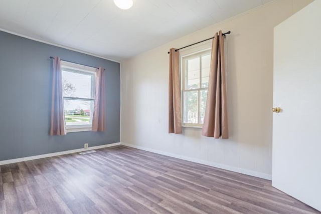 spare room with visible vents, baseboards, and wood finished floors