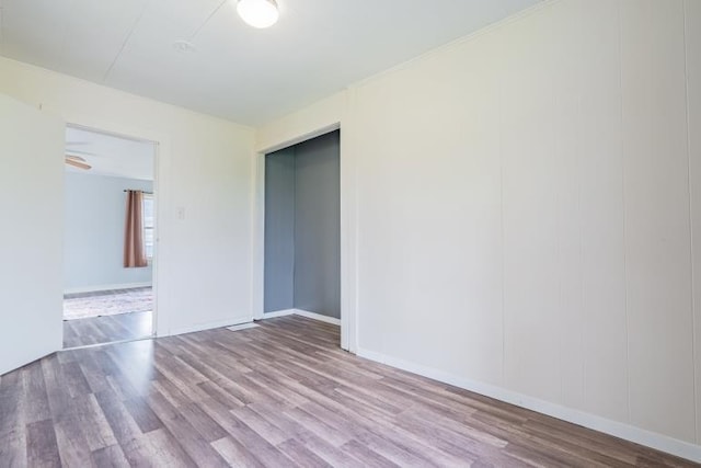 spare room with baseboards and wood finished floors