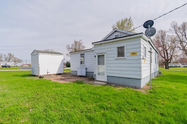 back of property featuring an outbuilding, a lawn, and a shed