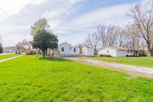 exterior space with a storage shed, a front yard, dirt driveway, and an outbuilding