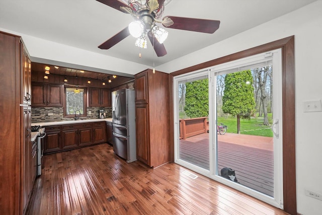 kitchen featuring appliances with stainless steel finishes, dark wood-style flooring, light countertops, a sink, and decorative backsplash
