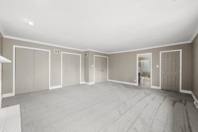 unfurnished bedroom with baseboards, light colored carpet, two closets, and ornamental molding