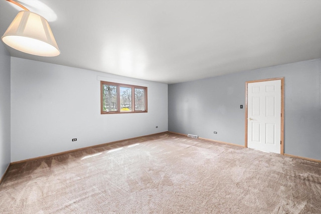 carpeted spare room with visible vents and baseboards