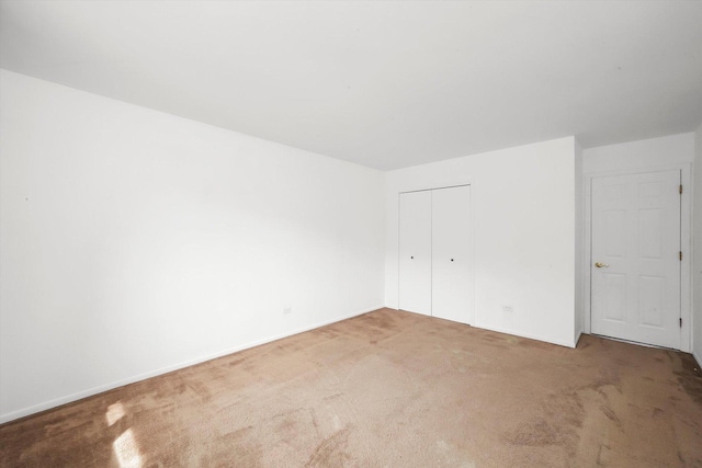 unfurnished bedroom with carpet floors, baseboards, and a closet