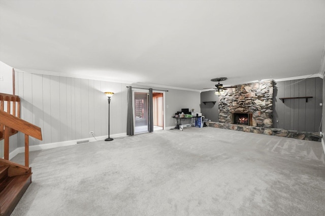 unfurnished living room featuring ornamental molding, a fireplace, a ceiling fan, visible vents, and carpet