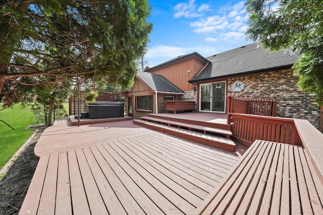 deck with a hot tub and a lawn