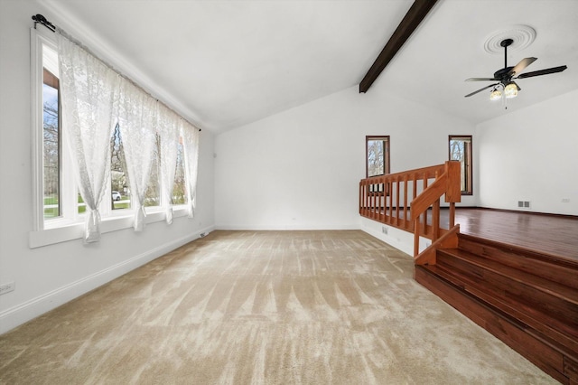unfurnished living room featuring ceiling fan, carpet, visible vents, vaulted ceiling with beams, and baseboards