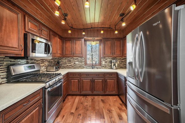 kitchen featuring rail lighting, light wood-type flooring, wood ceiling, light countertops, and stainless steel appliances