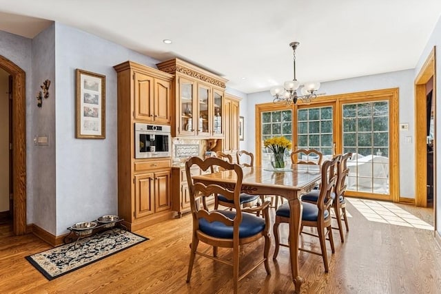 dining area with light wood-type flooring, baseboards, a chandelier, recessed lighting, and arched walkways