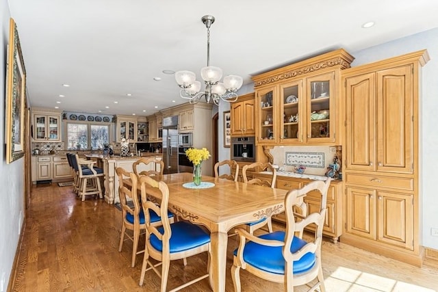 dining area featuring recessed lighting, light wood-style flooring, and an inviting chandelier