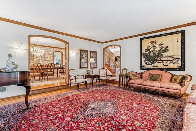 living area with arched walkways, wood finished floors, and ornamental molding