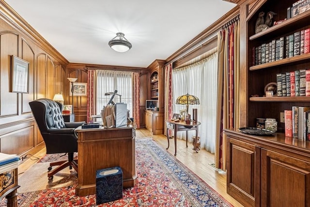 office with ornamental molding, built in features, and light wood finished floors