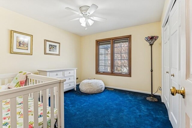 bedroom featuring a nursery area, dark carpet, a closet, visible vents, and baseboards