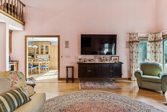 living area with a chandelier, a high ceiling, wood finished floors, and baseboards