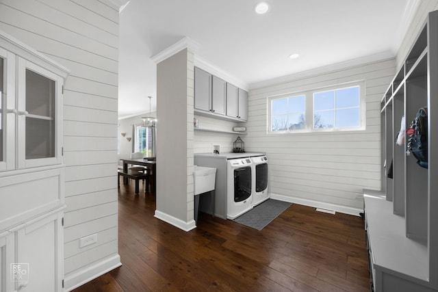 clothes washing area with washer and dryer, crown molding, dark wood-type flooring, and cabinet space