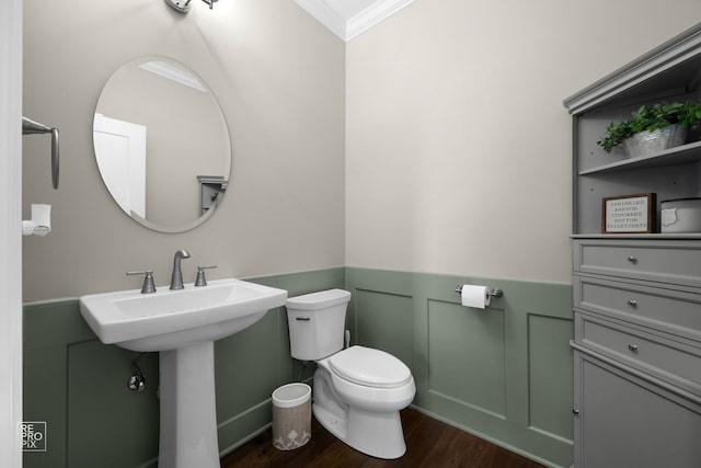 bathroom with ornamental molding, toilet, a wainscoted wall, a sink, and wood finished floors