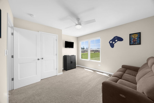 carpeted living area featuring baseboards and a ceiling fan