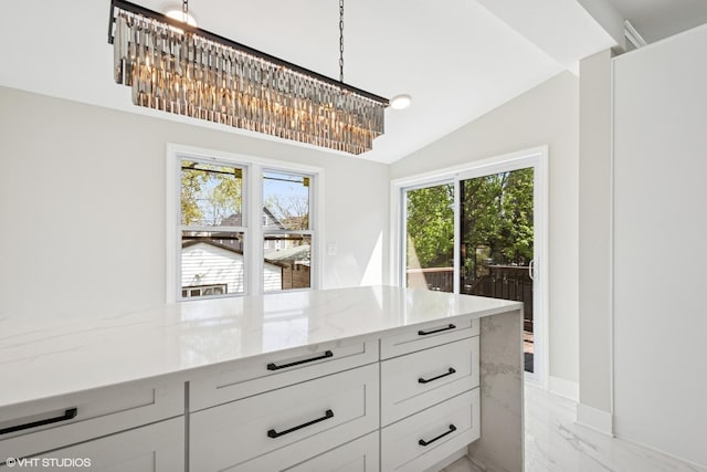 kitchen with white cabinets, light stone counters, appliances with stainless steel finishes, backsplash, and a notable chandelier